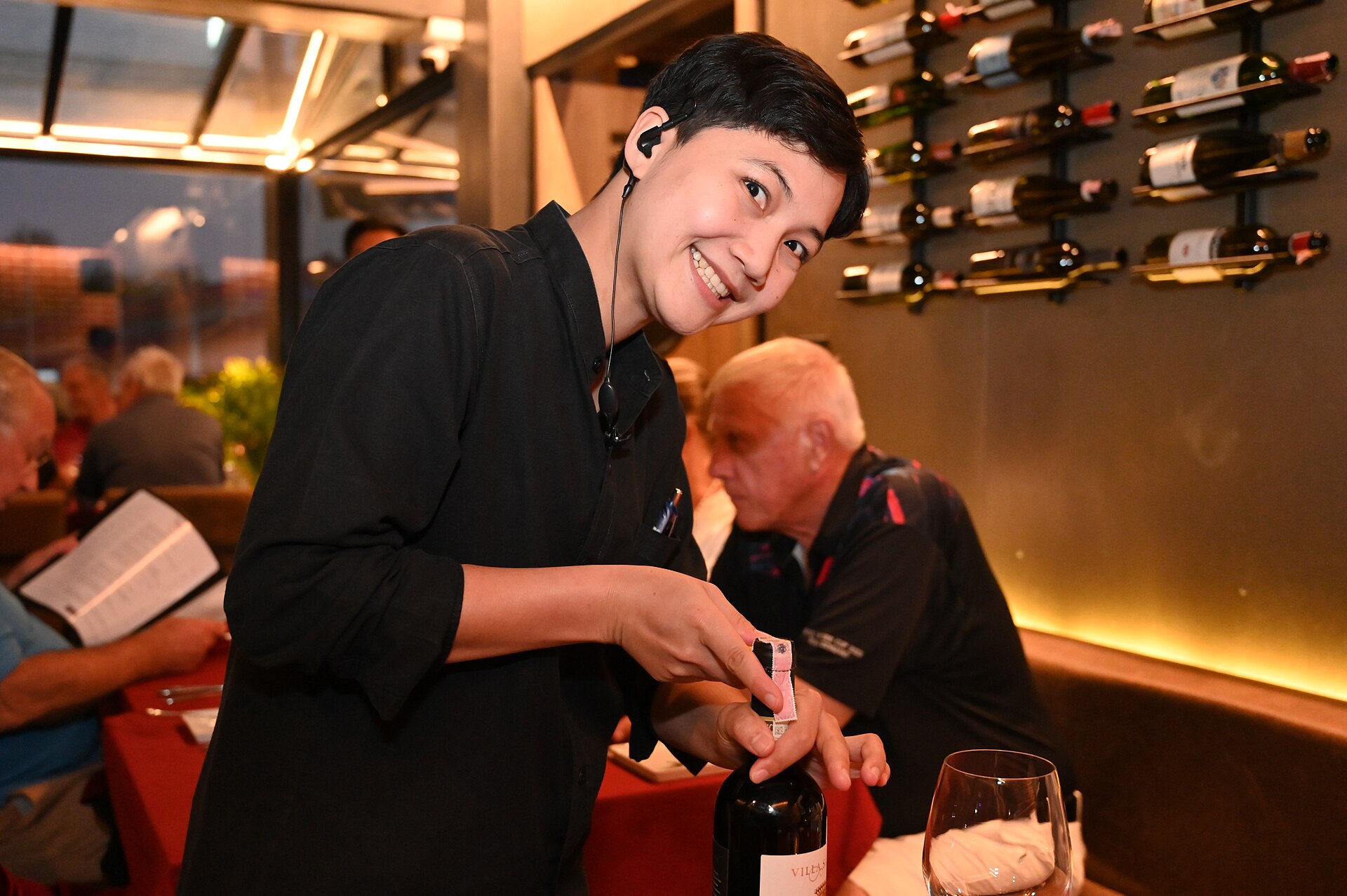 Server opent een fles wijn aan tafel in een restaurant
